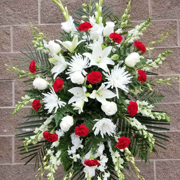 Standing funeral spray with white lilies, chrysanthemums, and red carnations