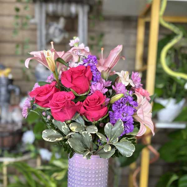 Pink roses and lilies arranged in a lavender textured vase