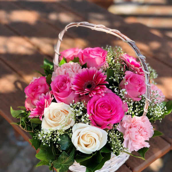 Pink and white roses with gerbera daisies in a white basket