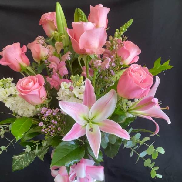 Pink roses and lilies in a glass vase with a pink ribbon