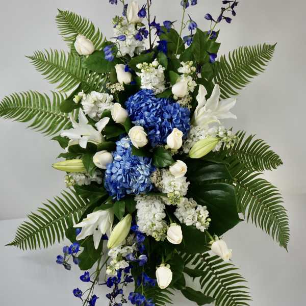 Tall blue and white floral spray with lilies, roses, and ferns