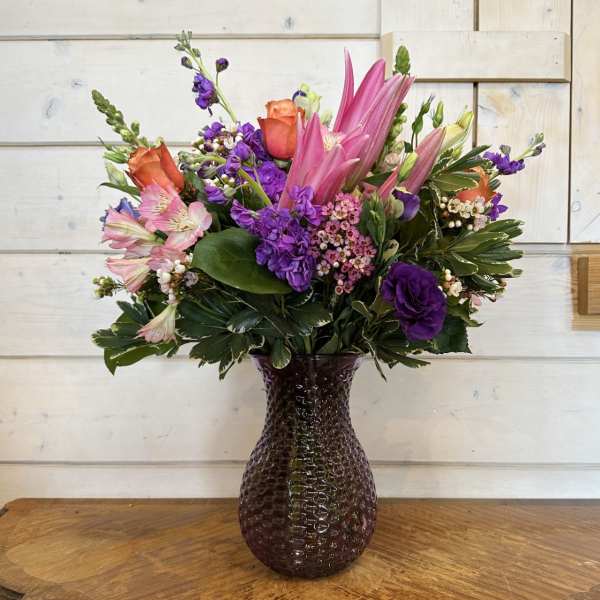 Pink and purple mixed bouquet in a dark glass vase