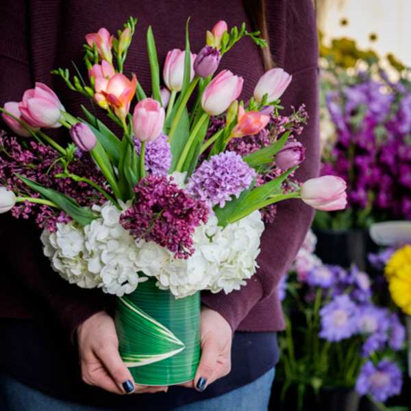 Pink tulips and purple flowers arranged in a green vase