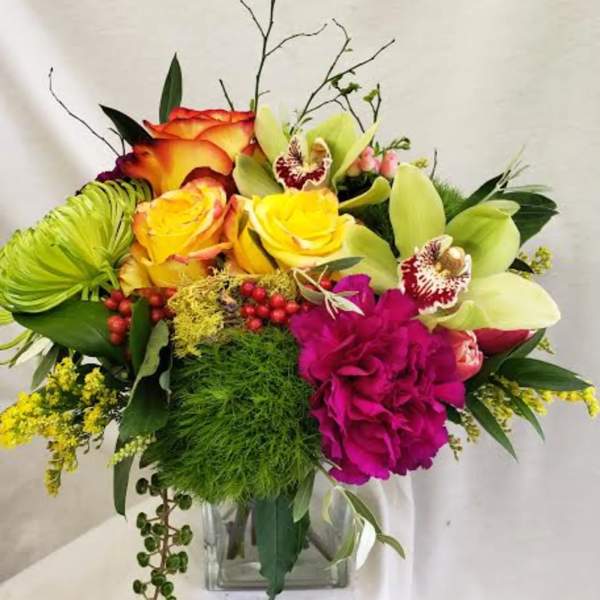 Colorful bouquet with roses, orchids, and a glass vase