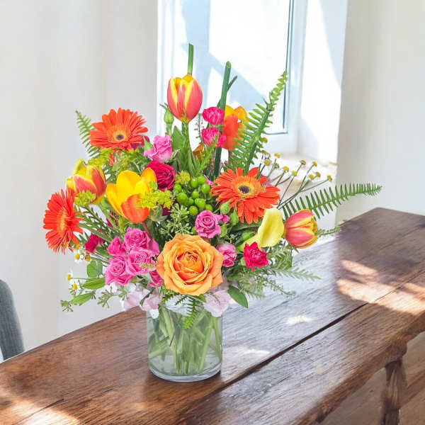 Colorful mixed bouquet in a clear glass vase on a wooden table