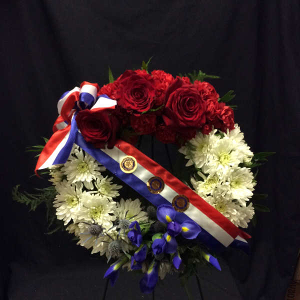Red roses and white daisies arranged as a wreath with ribbon and medals