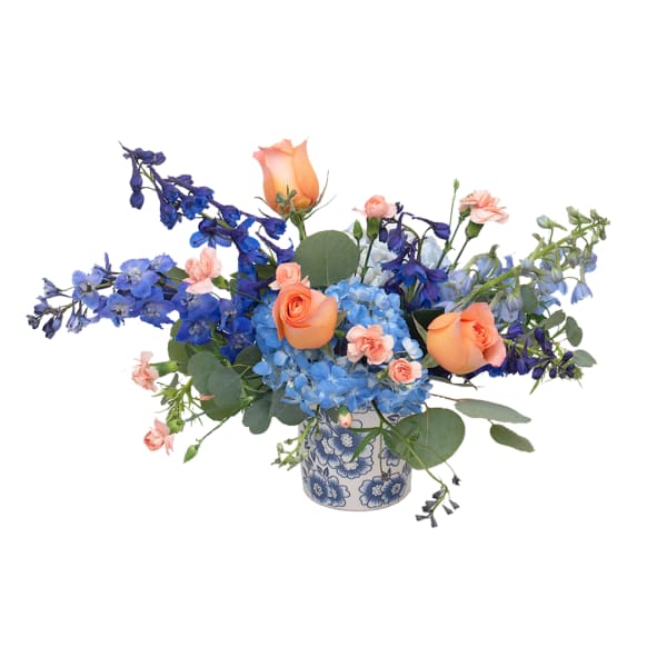 Blue and peach floral arrangement in a patterned ceramic vase
