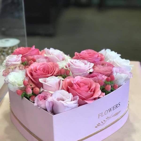 Pink and white roses arranged in a heart-shaped box