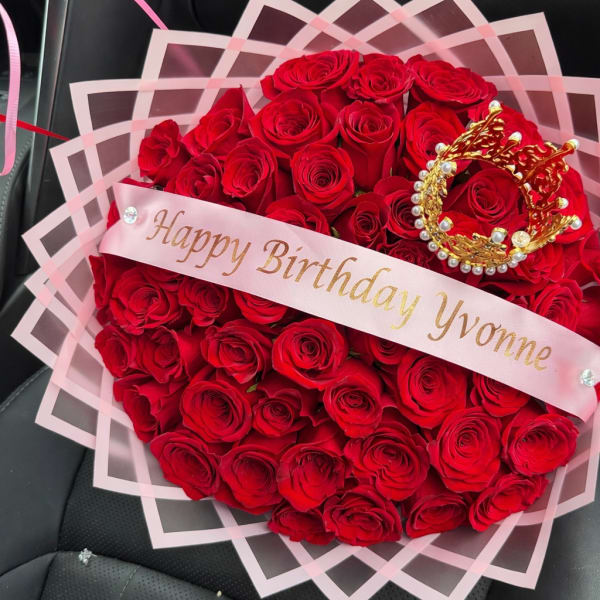 Heart-shaped bouquet of red roses with a birthday ribbon and crown decoration