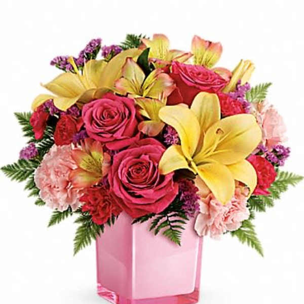 Pink roses and yellow lilies arranged in a pink glass vase