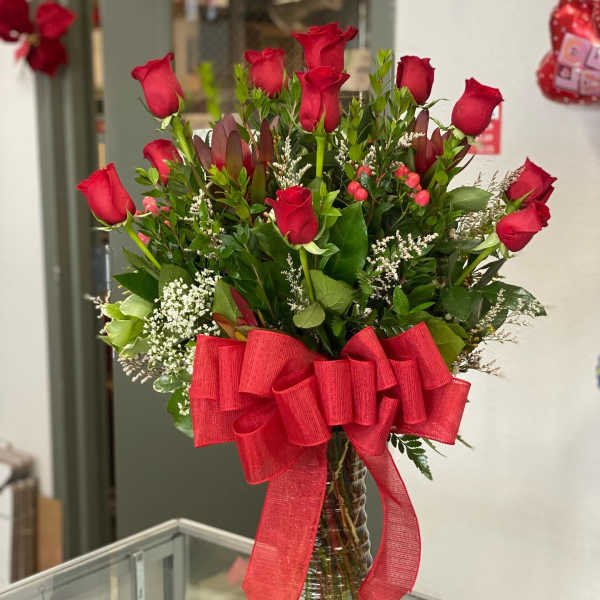 Bouquet of red roses in a clear glass vase with a large red ribbon