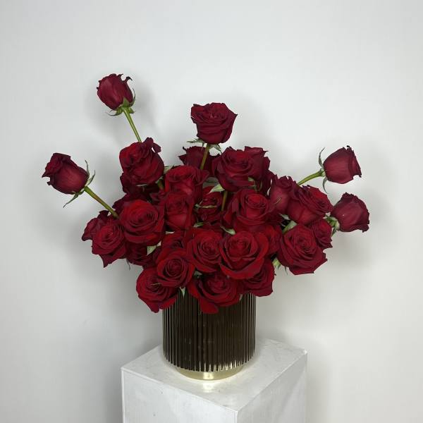 Red roses arranged in a tall ribbed vase