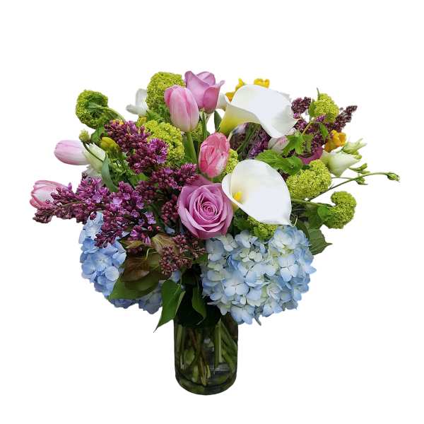 Mixed bouquet with pink tulips, white calla lilies, and blue hydrangeas in a glass vase