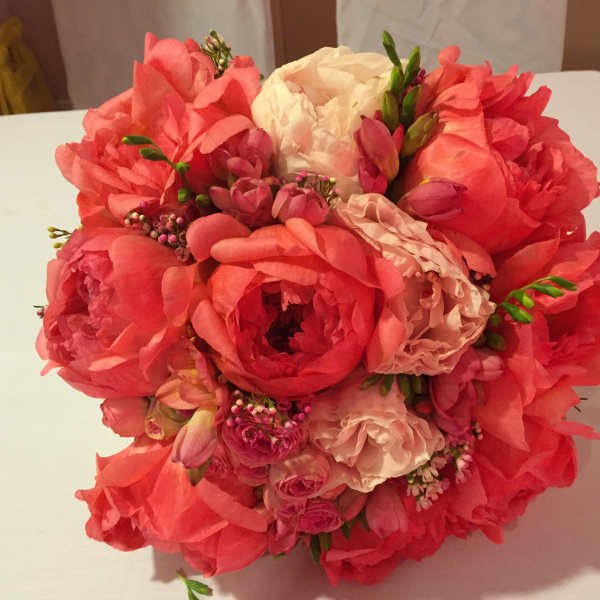 Round bouquet of coral and blush flowers with white blooms