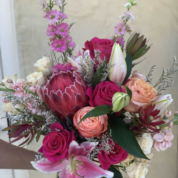 Hand-tied bouquet with pink roses, lilies, and a protea