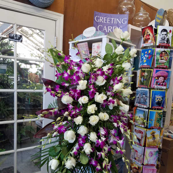 Tall arrangement of white roses and purple orchids on a stand