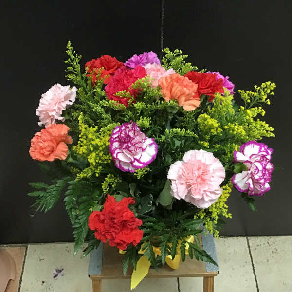 Mixed carnations in bright colors with yellow filler in a vase