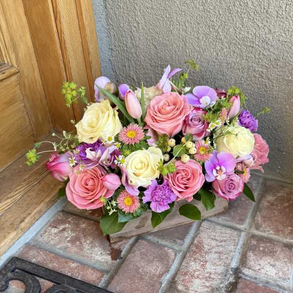 Pink and cream rose bouquet with purple accents in a low wooden box