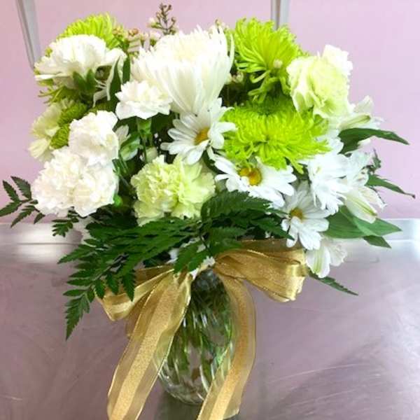 White and lime-green bouquet in a glass vase with a gold ribbon