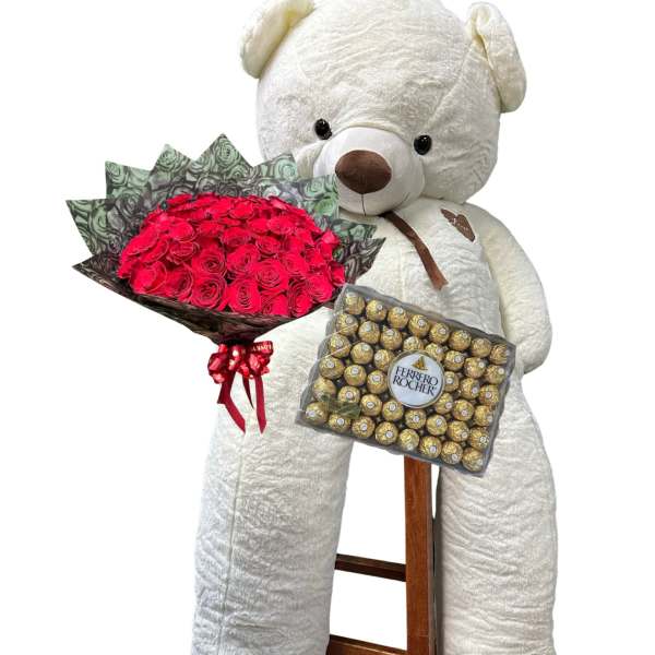 Large teddy bear holding a bouquet of red roses and a box of Ferrero Rocher chocolates