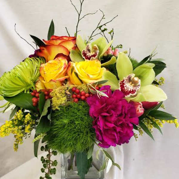 Bright mixed bouquet with roses, orchids, and a glass vase