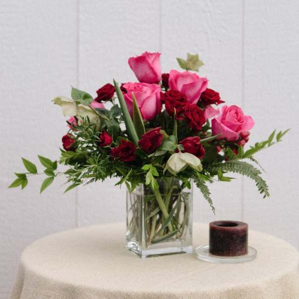 Pink and red roses arranged in a clear glass vase