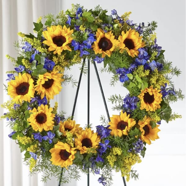 Sunflower wreath with blue flowers on a black stand