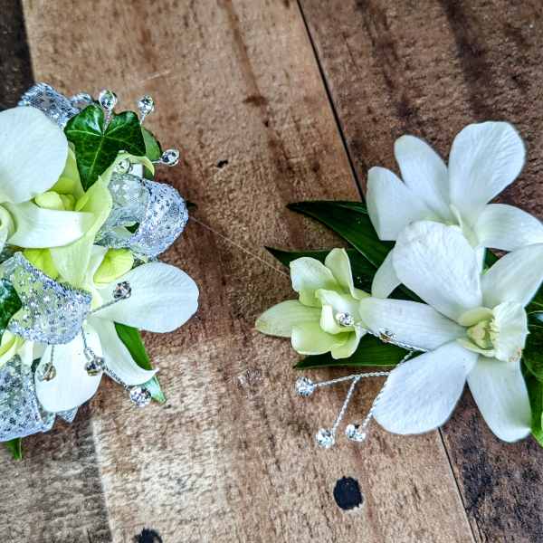 Two white orchid corsages with silver ribbon and bead accents