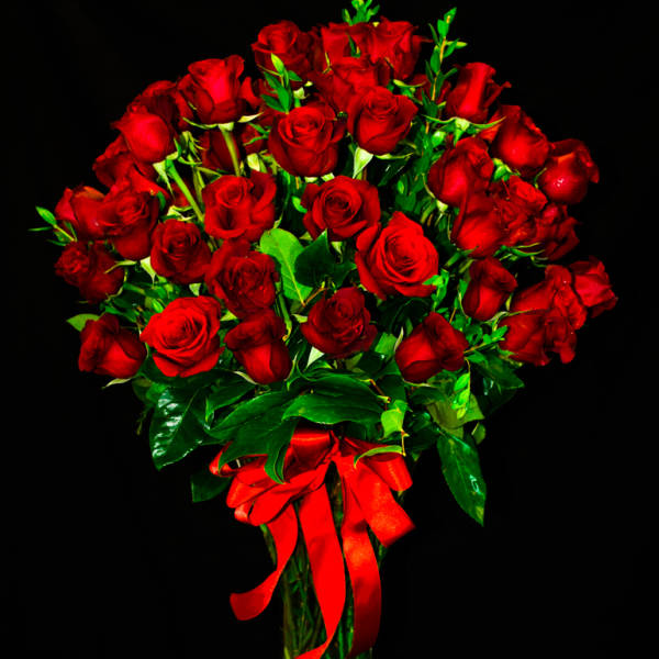 Bouquet of red roses in a clear glass vase with a red ribbon