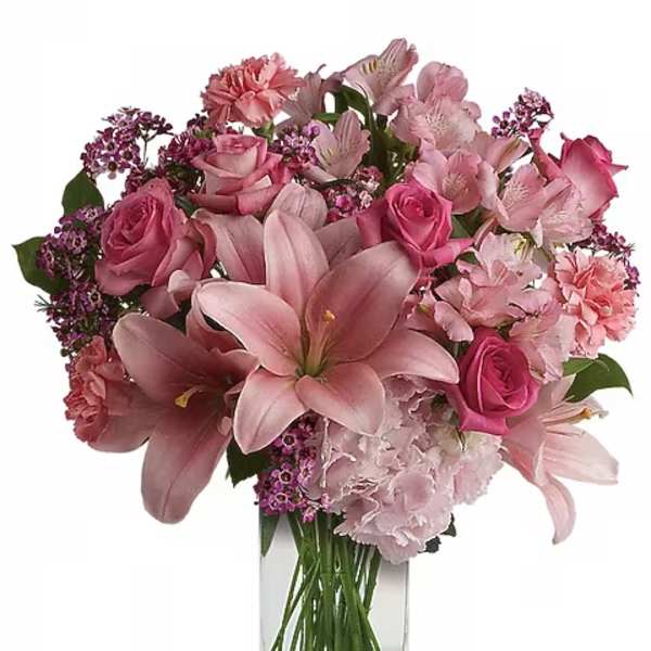 Pink lilies, roses, and alstroemeria in a clear glass vase