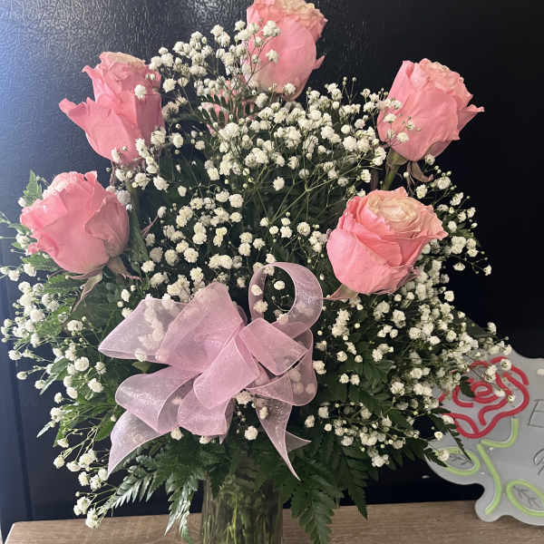 Pink roses with baby's breath in a glass vase and pink ribbon