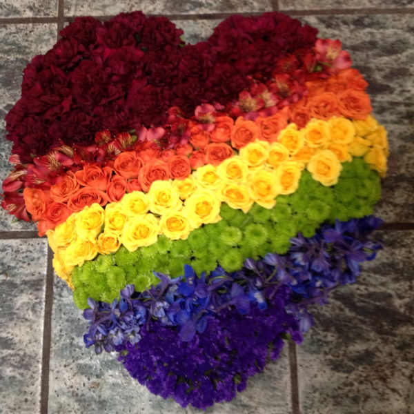 Heart-shaped floral arrangement in rainbow colors on a tiled floor