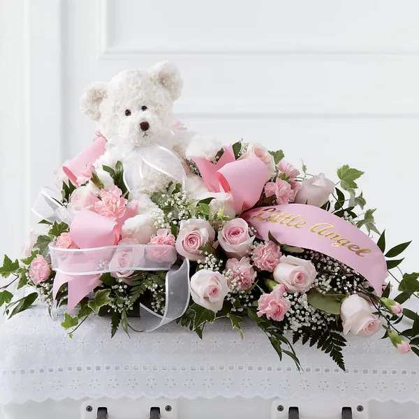 Pink rose arrangement with a white teddy bear and ribbon