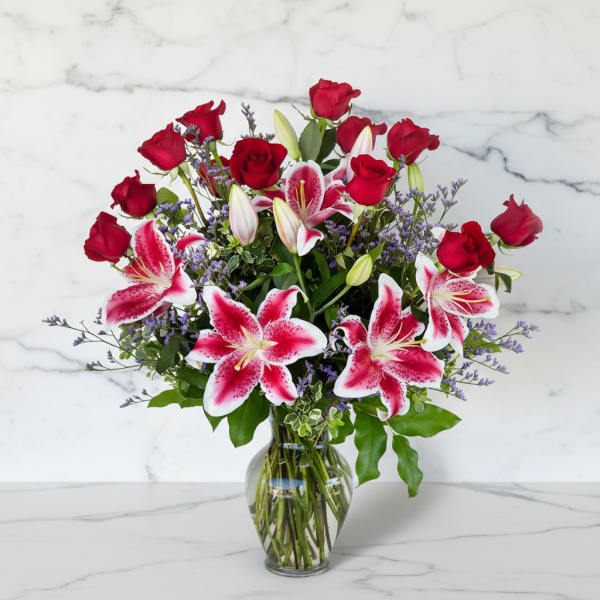 Red roses and pink lilies in a clear glass vase