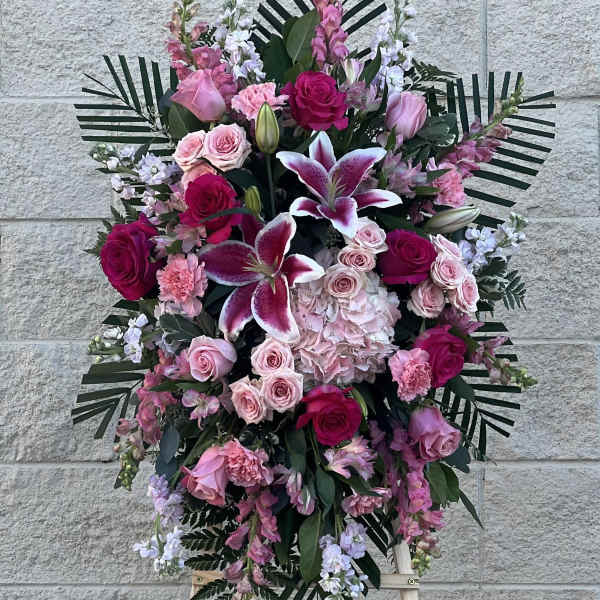 Standing floral spray with pink and white roses and lilies on an easel