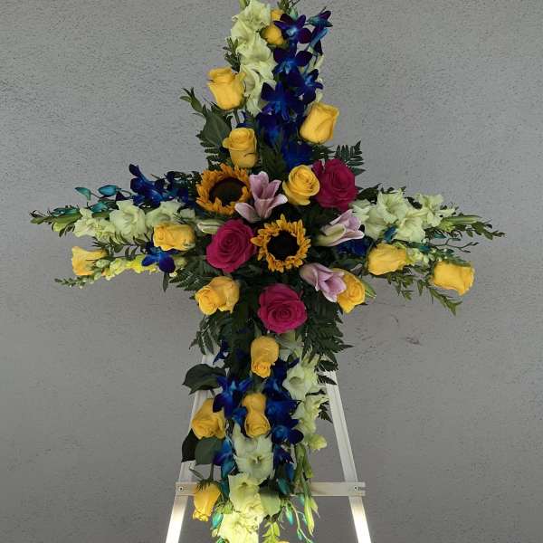 Cross-shaped floral tribute on an easel with roses and orchids