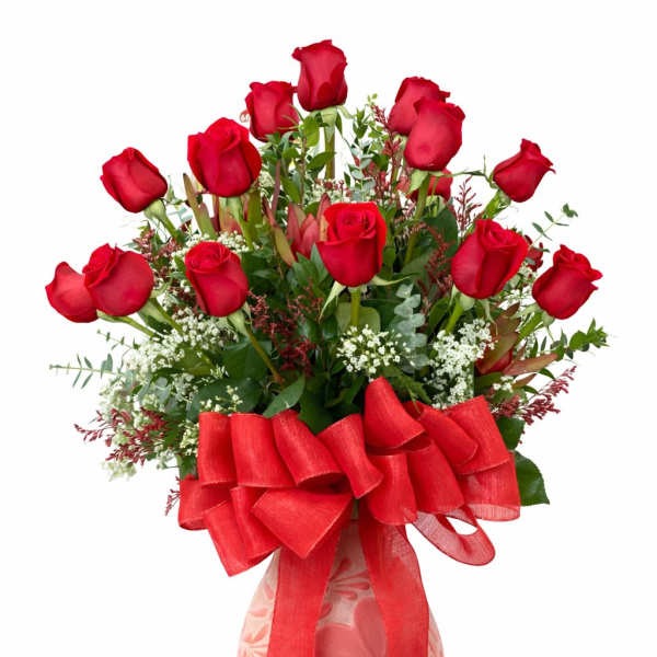 Red roses arranged in a pink patterned vase with a large red bow