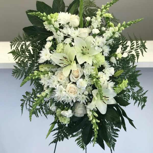 White floral standing spray with lilies, roses, and chrysanthemums