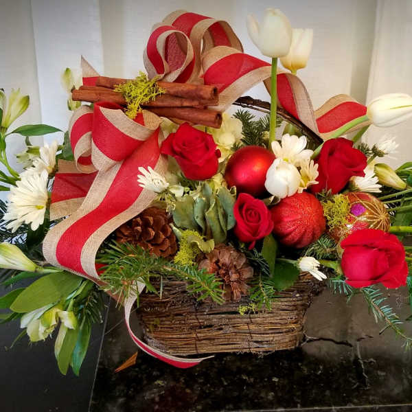 Basket arrangement with red roses, white flowers, and holiday ribbon