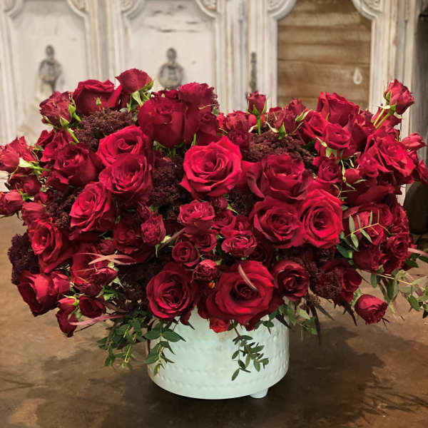 Large arrangement of red roses in a white container