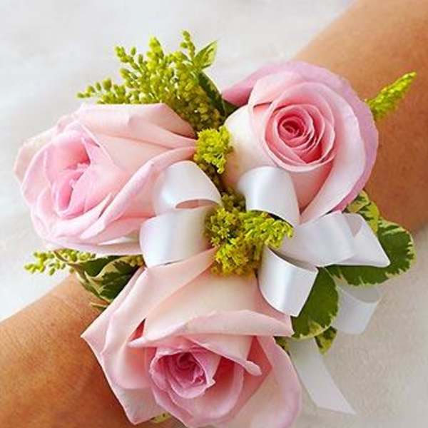Pink rose wrist corsage with white ribbon and green accents