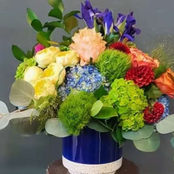 Colorful mixed flower arrangement in a blue ceramic vase
