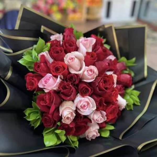 Bouquet of red and pink roses wrapped in black paper