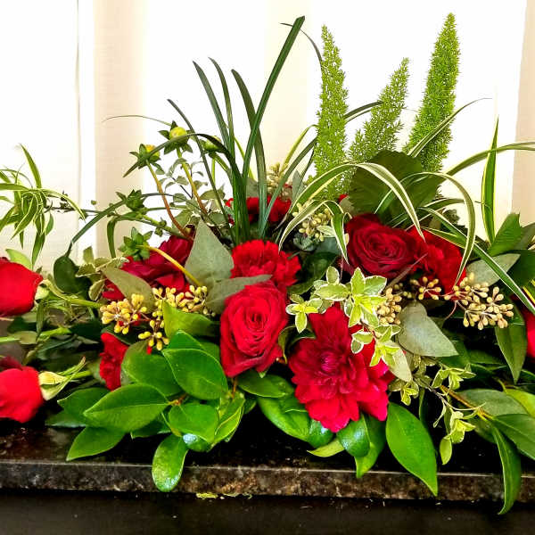 Red roses and carnations arranged on a low rectangular base