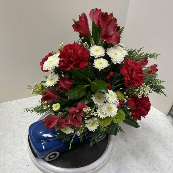 Red and white floral arrangement in a blue car-shaped container