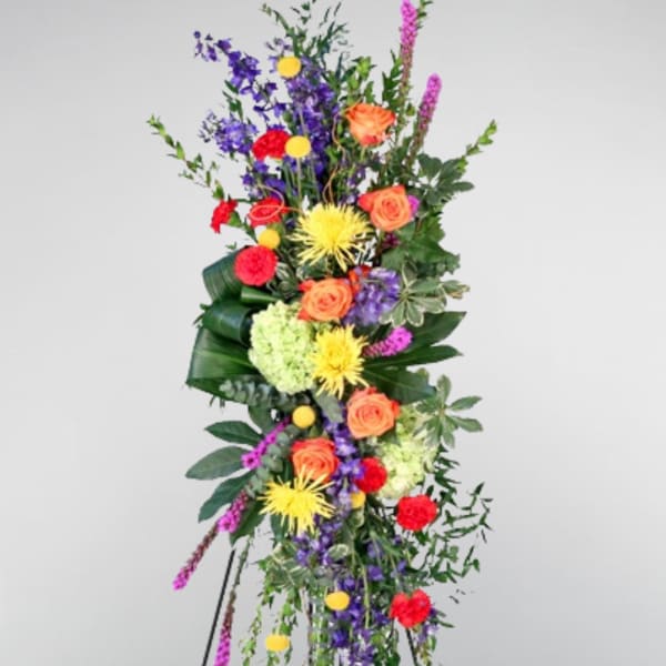 Tall standing floral spray with orange roses, purple blooms, and yellow flowers