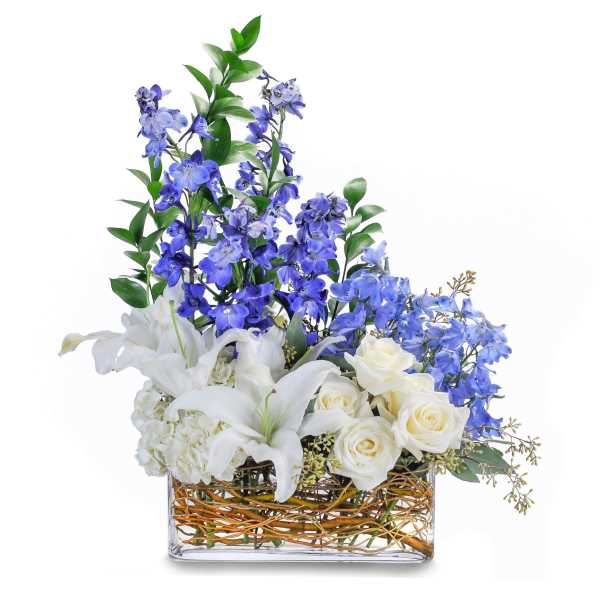 Tall blue and white flower arrangement in a rectangular glass vase with woven branches inside