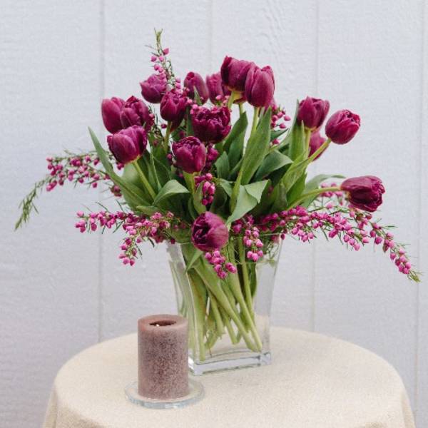 Magenta tulips in a clear glass vase with pink filler flowers