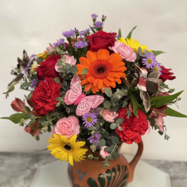 Colorful mixed bouquet in a terracotta vase with a butterfly decoration