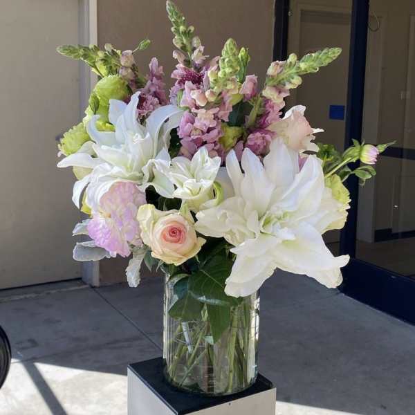 White lilies and pink flowers arranged in a clear glass vase
